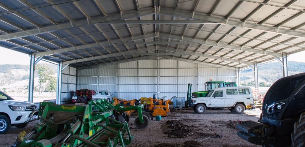 large farm shed with farm machinery, equipment and vehicles inside