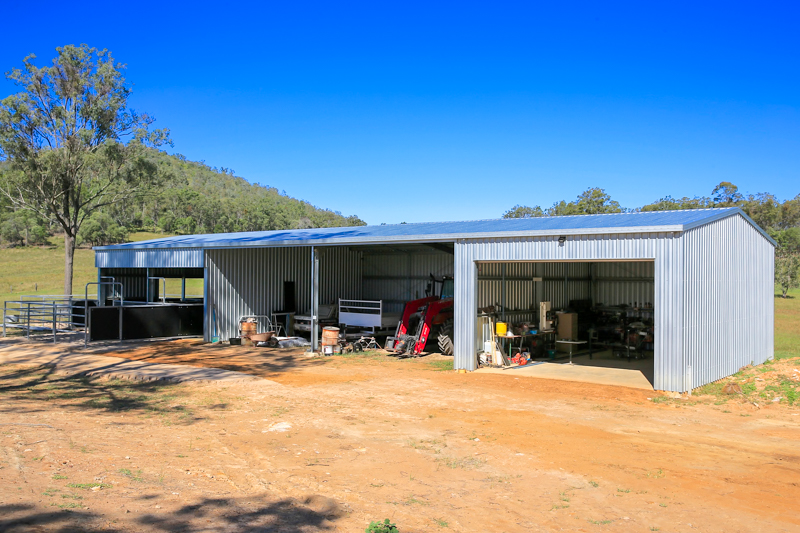 Custom farm shed with enclosed workshop, open storage bays and livestock pen area