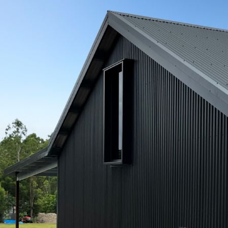 Close up of finished two-bay custom steel garage with man cave and gable overhang.