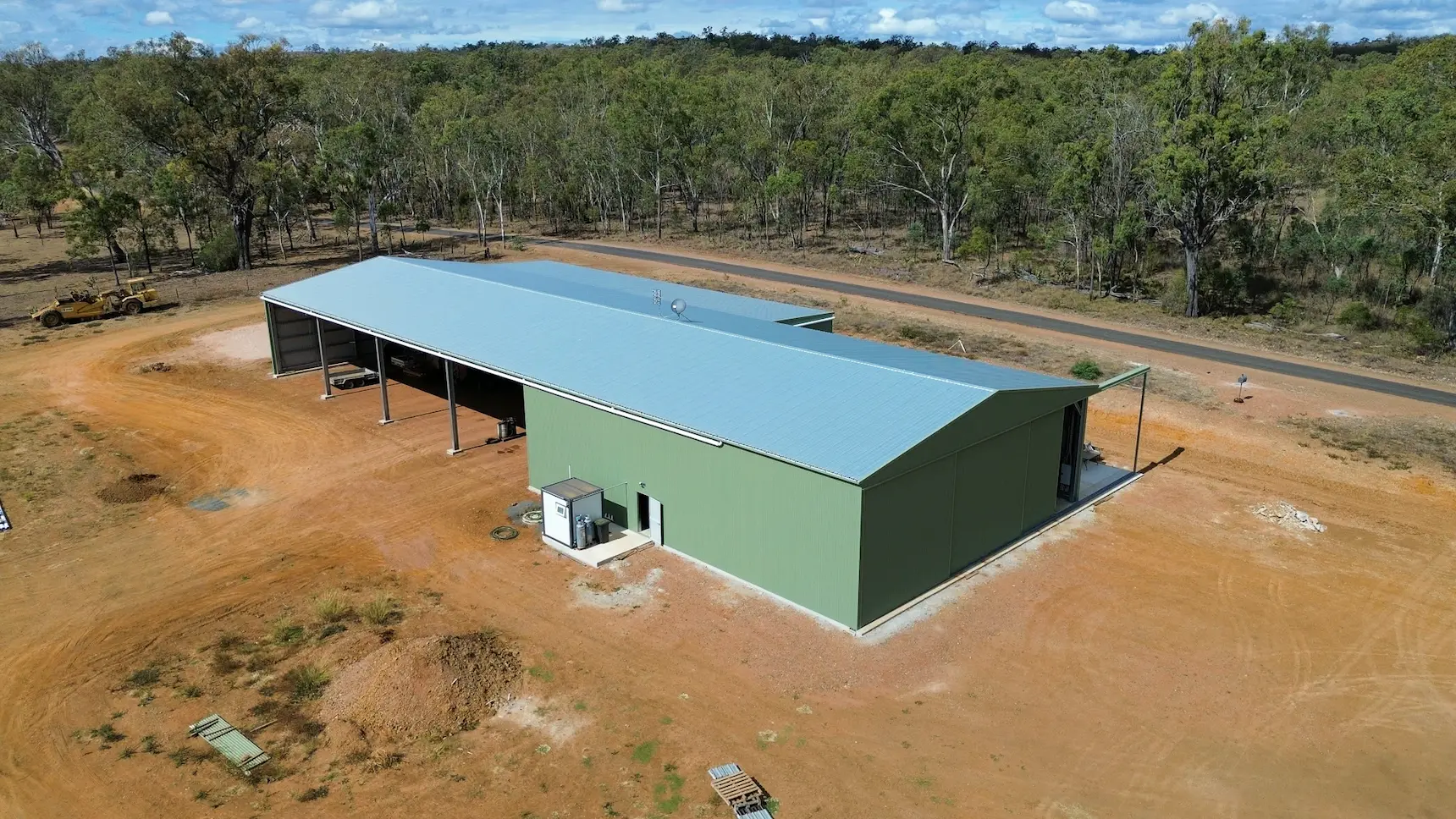 Aerial view of a custom farm shed with open machinery bays and enclosed storage.